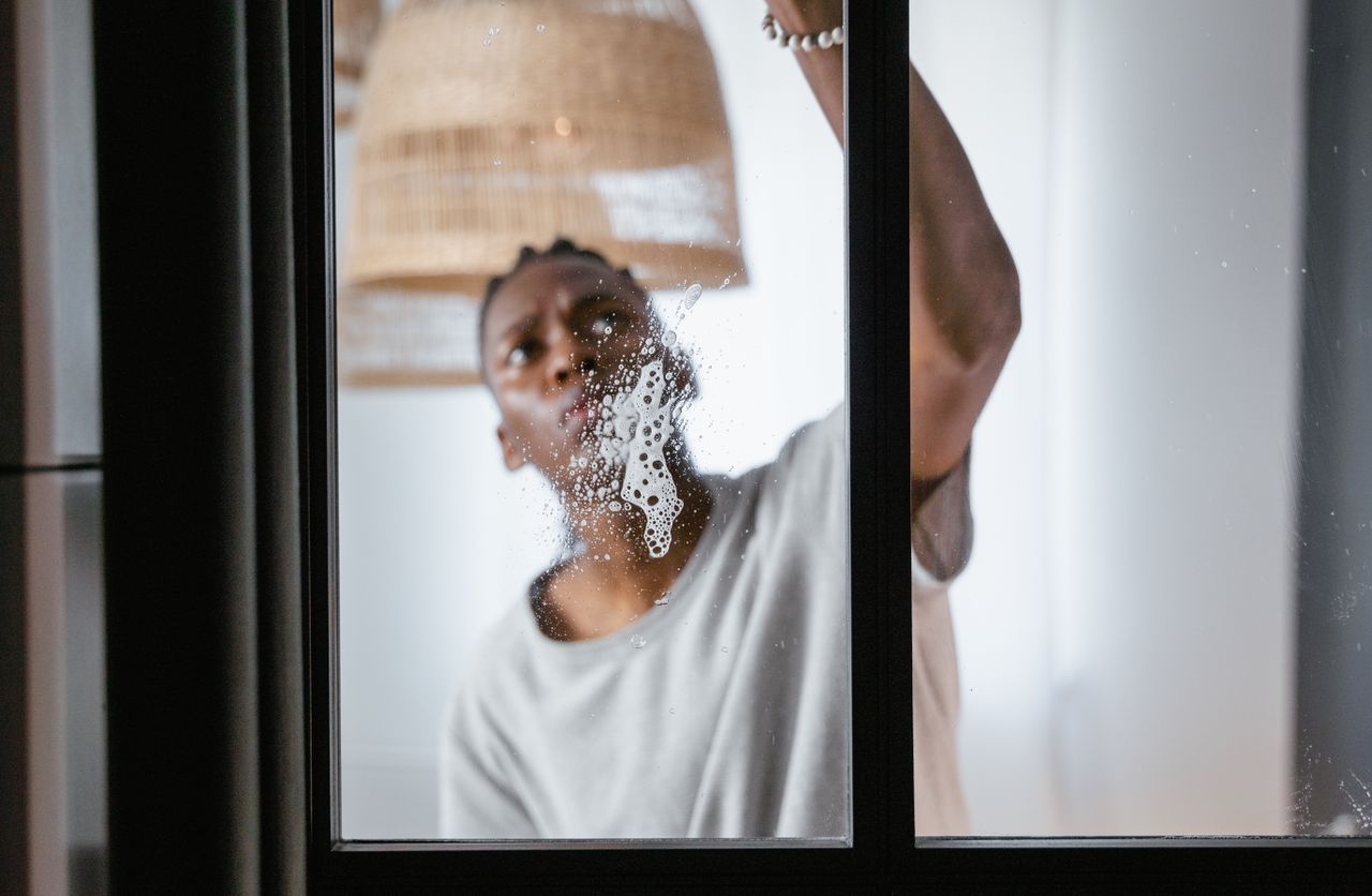 hero-img-01 An adult male cleaning a glass window indoors, focusing on household chores and cleanliness.
